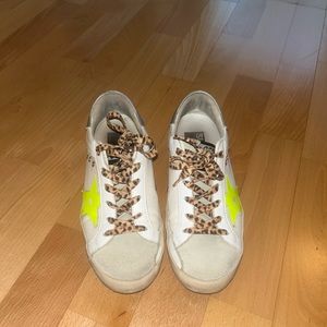Golden Goose sneakers with white leather, leopard laces and yellow star detail.
